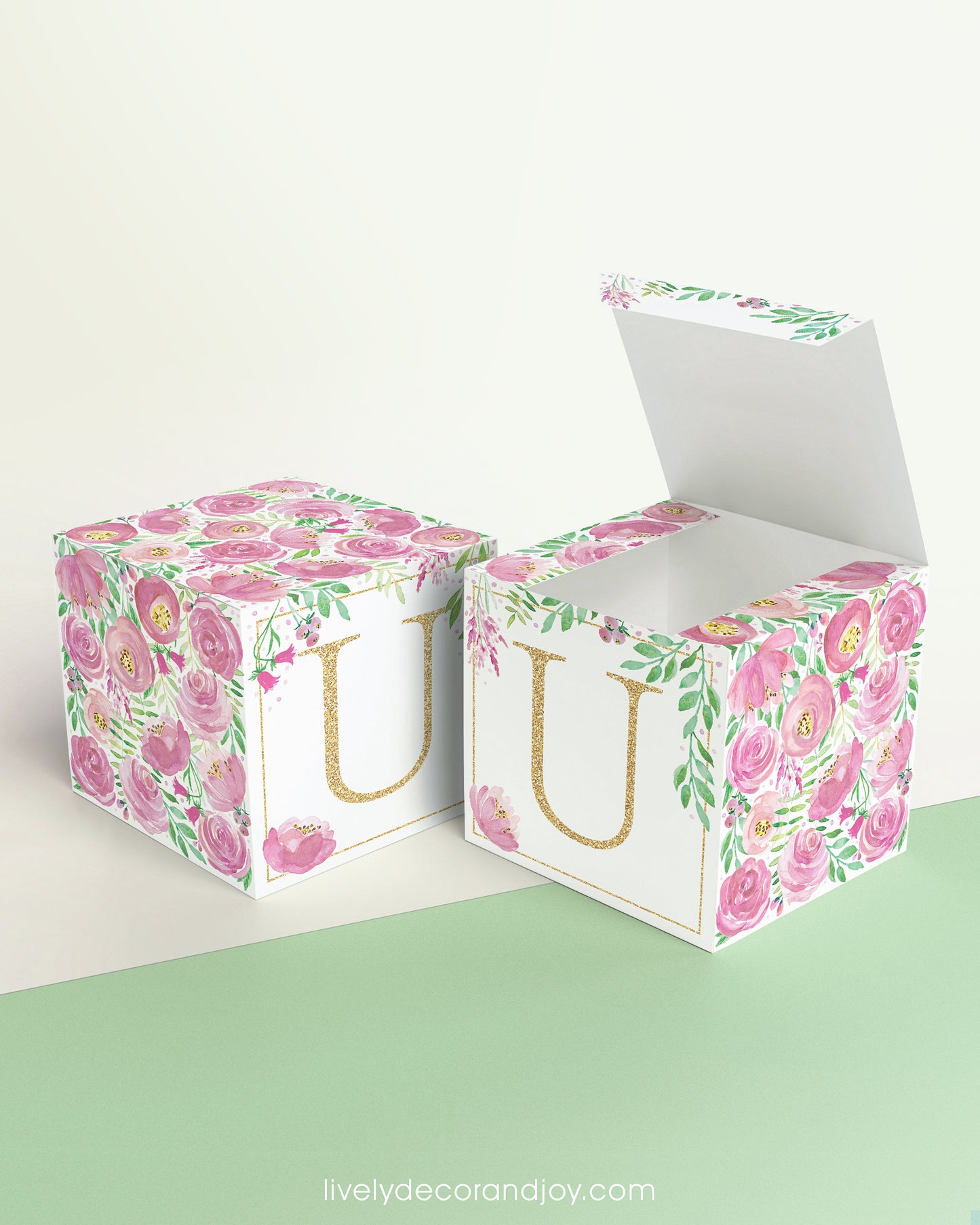 Two printed DIY paper cubes have the same designs, one of which has an open lid, showing that it is a box.