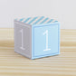 Paper cube in tints of blue and light grey and the number 1 on the sides. Made from a printable design.