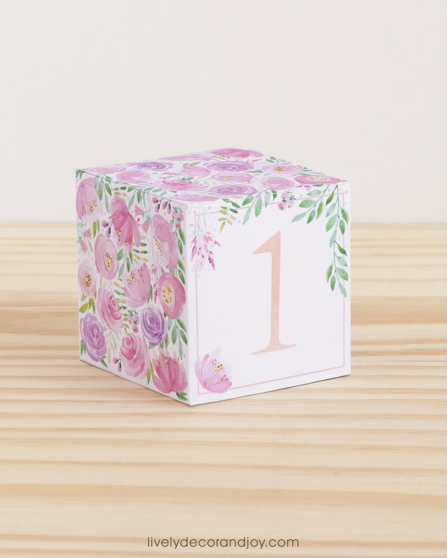 Paper cube with floral motifs in blush and lavender and the number 1 in peach on the front. Made from a printable design.