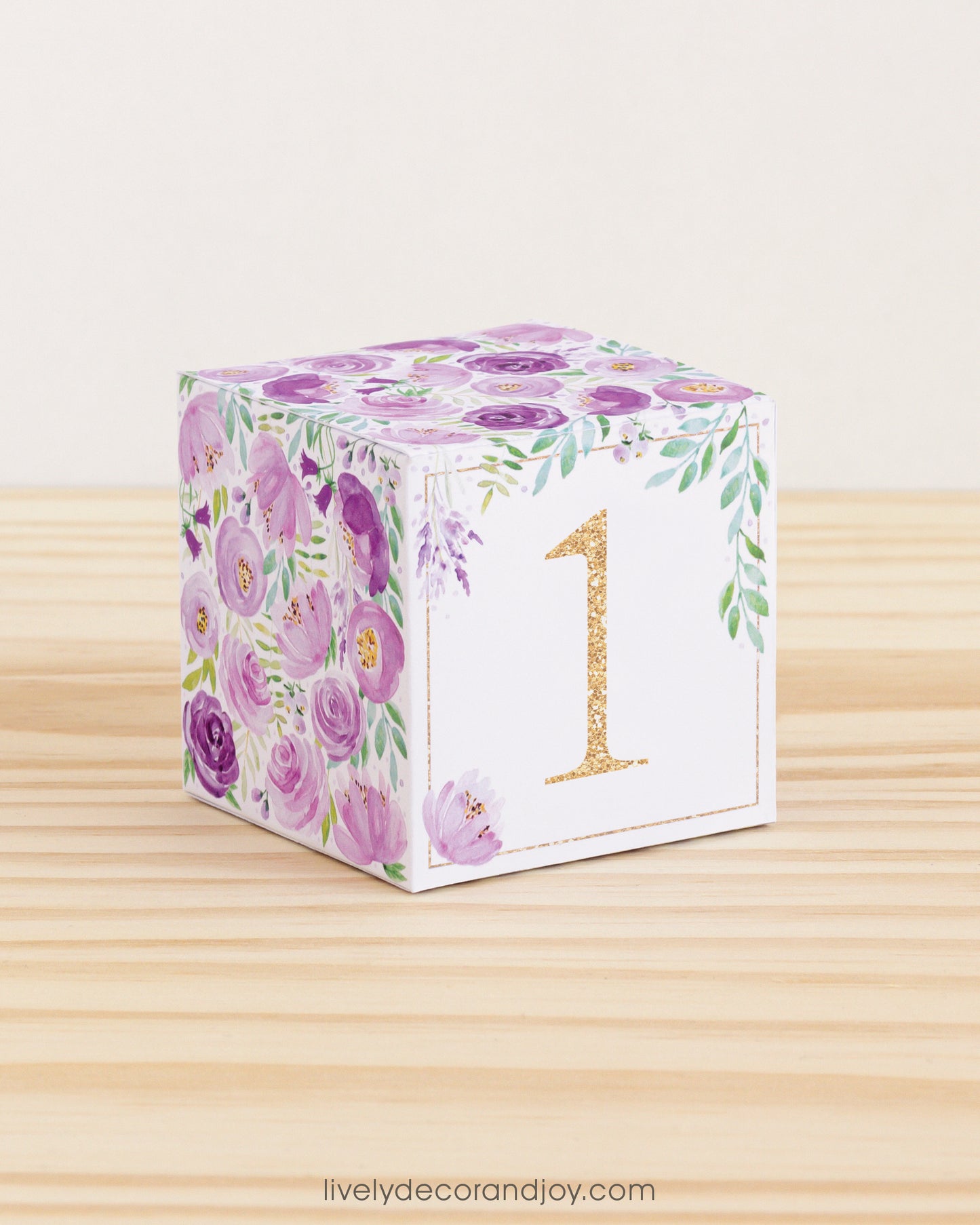 Paper cube with floral motifs in purple and green and the number 1 in gold on the front. Made from a printable design.