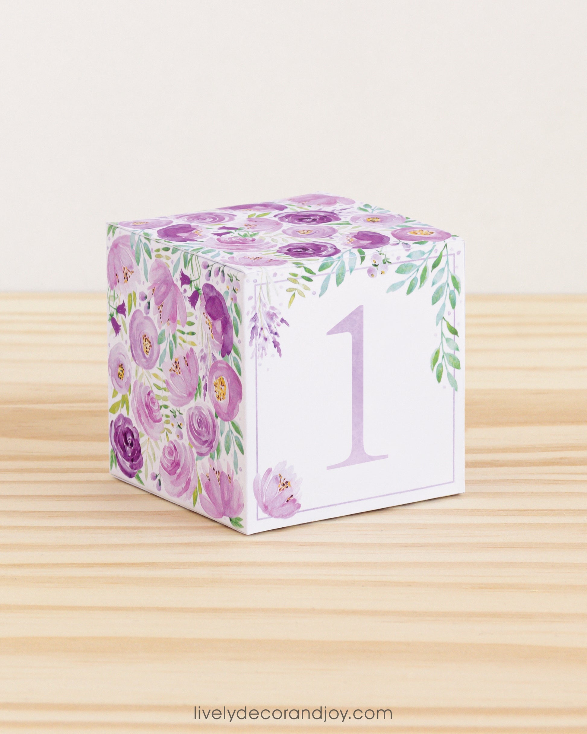 Paper cube with floral motifs in purple and green and the number 1 in lavender on the front. Made from a printable design.