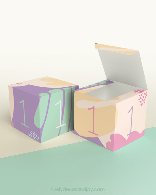 Paper cube shown as a block and as an open box. Designed in pastel colors. Has the number 1 on the sides.