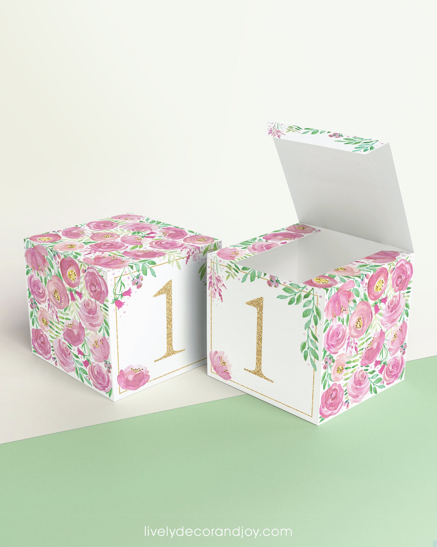 Paper cube shown as a closed block and also as an open box. It has pink floral designs and the number 1 in gold.