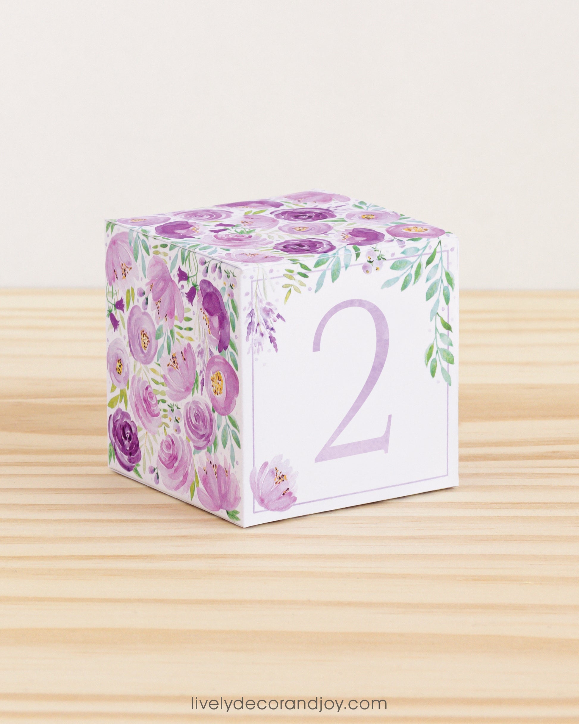 Baby block with purple and pink flowers and the number 2 in a lavender glitter-like pattern on the front.