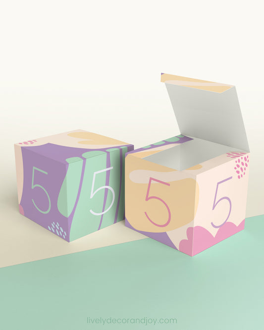 Two building blocks made of printed paper feature the same design. One is open like a box.
