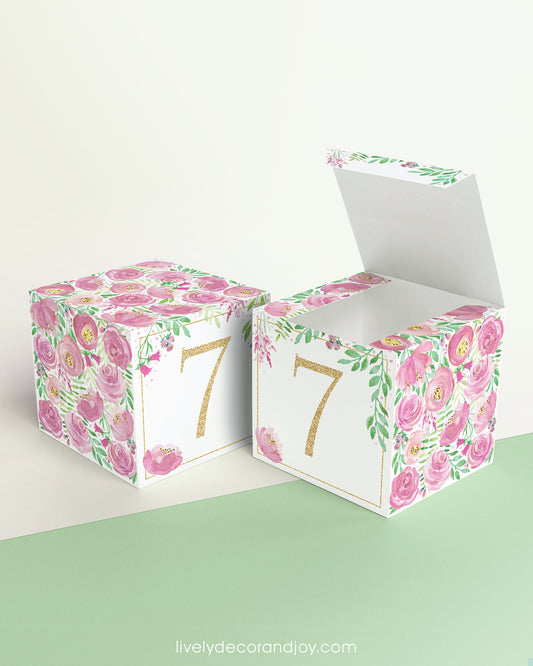Two paper building blocks made with the same pink floral design and the number 7 in gold. One has the top lid open.
