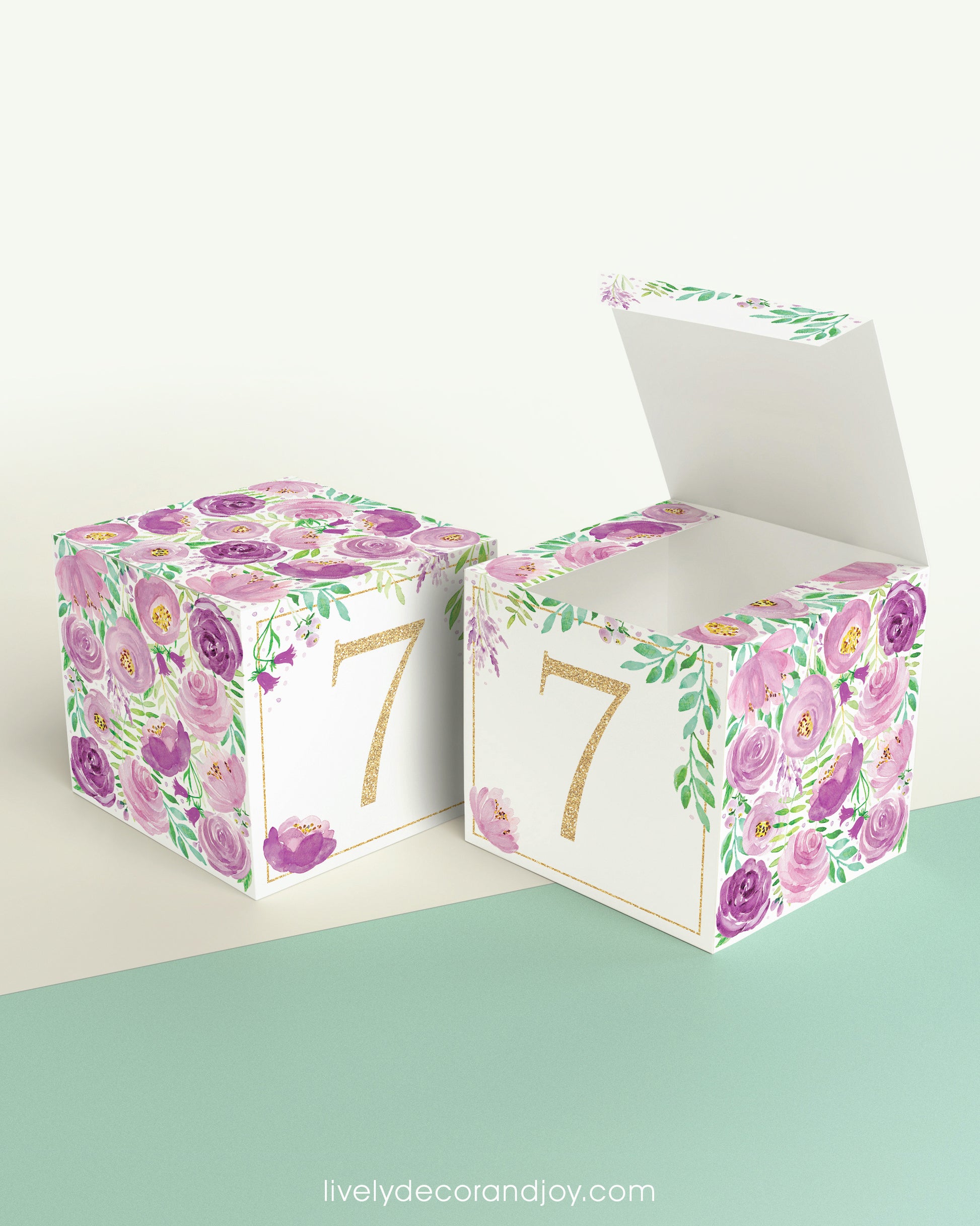 Two paper building blocks made with the same purple floral design and the number 7 in gold. One has the top lid open.