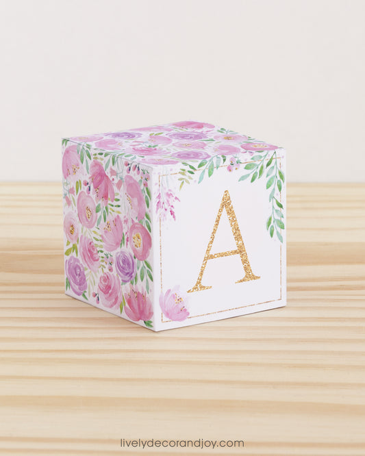 Large DIY block with the letter A in peach and floral designs in blush and lavender.The paper cube is on a wooden table.