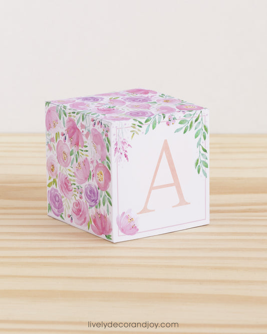 Large DIY block with the letter A in peach and floral designs in blush and lavender.The paper cube is on a wooden table.