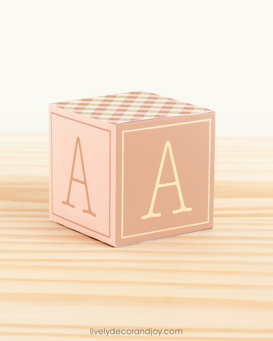 Large DIY building block with the letter A in cottagecore colors.The paper cube is on a wooden table.