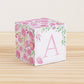 Large DIY block with the letter A in pink and floral designs in pink and green.The paper cube is on a wooden table.