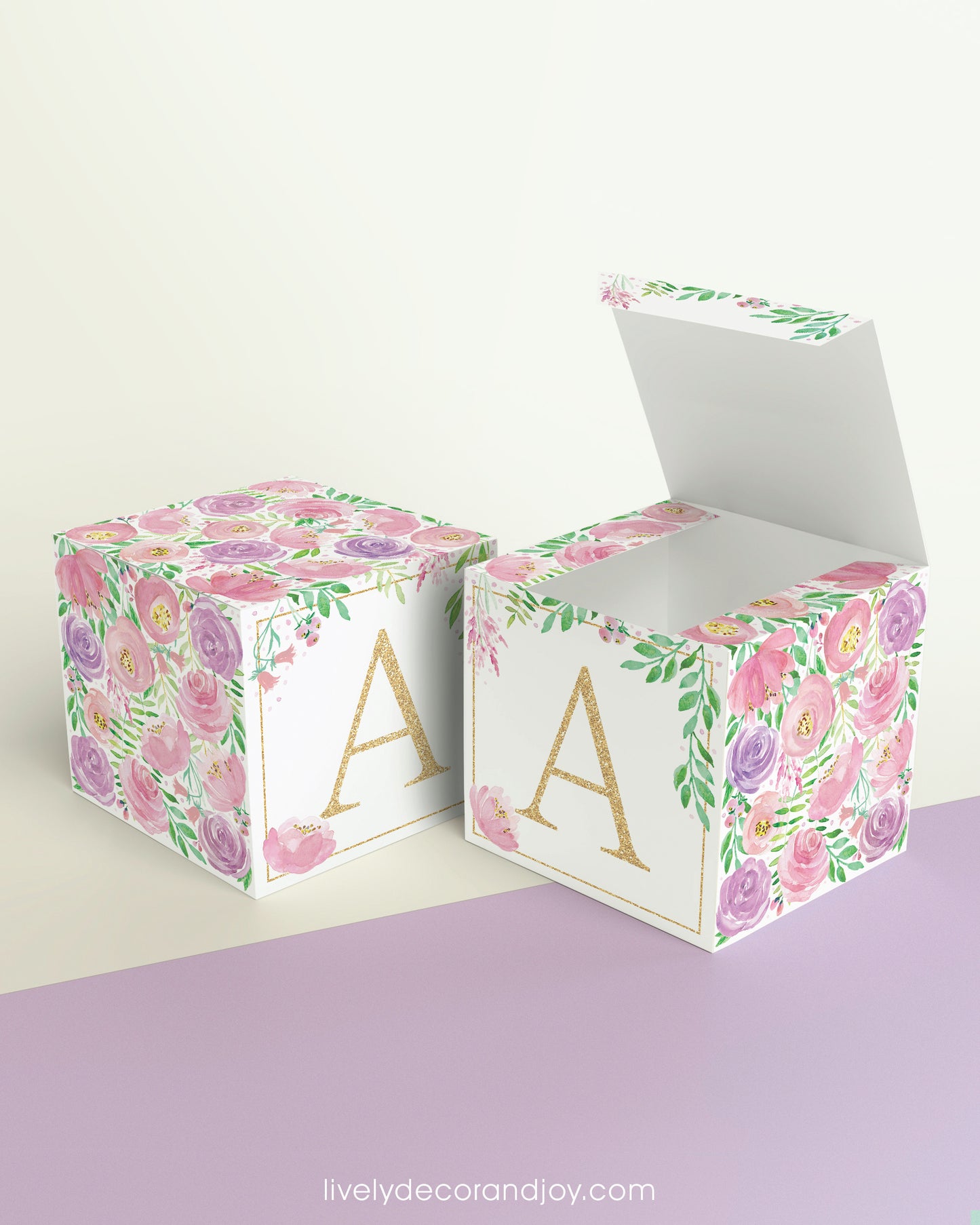 Two paper cubes with the same floral design and a capital A on the front. One has the lid open showing it can also be a box.