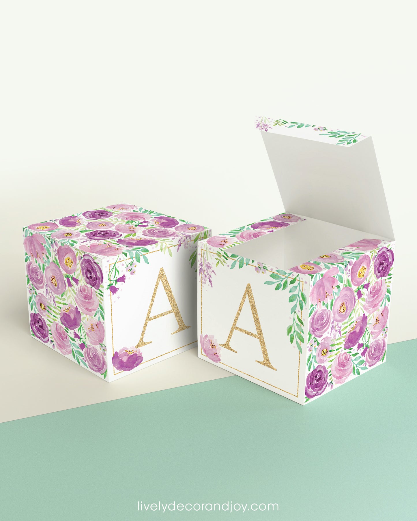 Two paper cubes with the same floral design and a capital A on the front. One has the lid open showing it can also be a box.
