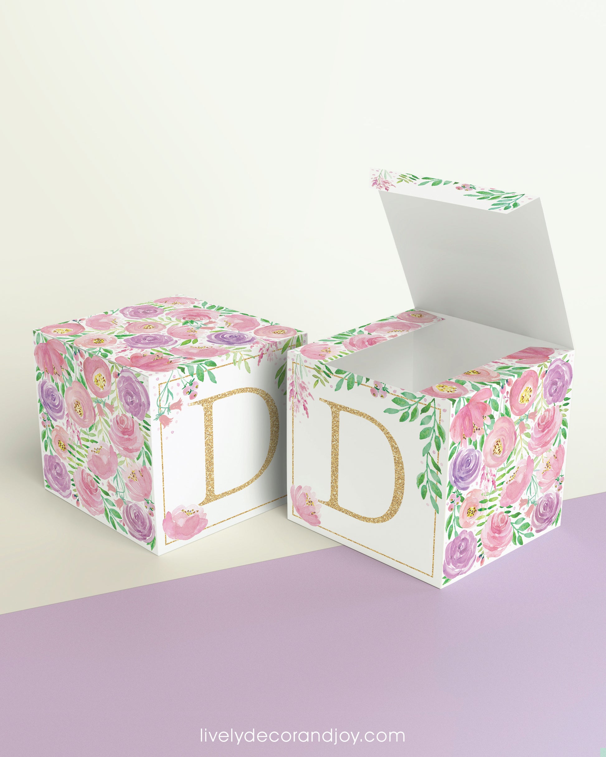 Two paper cubes with floral designs and the letter D in peach. One has the top open, showing it can be a cube or a box.
