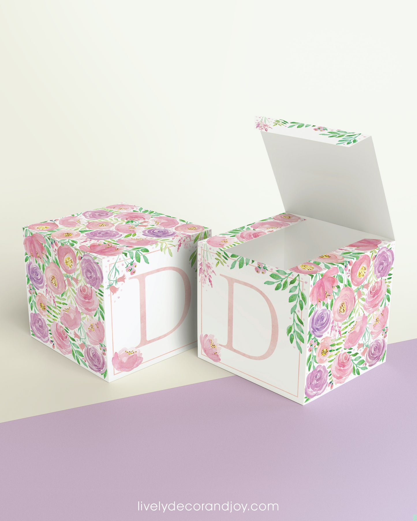 Two paper cubes with floral designs and the letter D in peach. One has the top open, showing it can be a cube or a box.