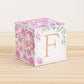 Paper building block features watercolor flowers and leaves in shades of pink and green. A gold capital F is on the front.