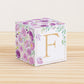 Paper building block features watercolor flowers and leaves in shades of purple and green. A gold capital F is on the front.