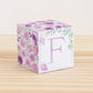 Paper building block features watercolor flowers and leaves in shades of purple and green. A lilac capital F is on the front.