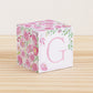 Letter block with printed pink and green floral designs and a pink capital G on the front. It is made of paper.