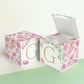 Two blocks made of paper, one has the top lid open. Floral designs cover all sides except the front, which has the letter G.