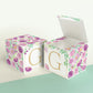Two blocks made of paper, one has the top lid open. Floral designs cover all sides except the front, which has the letter G.