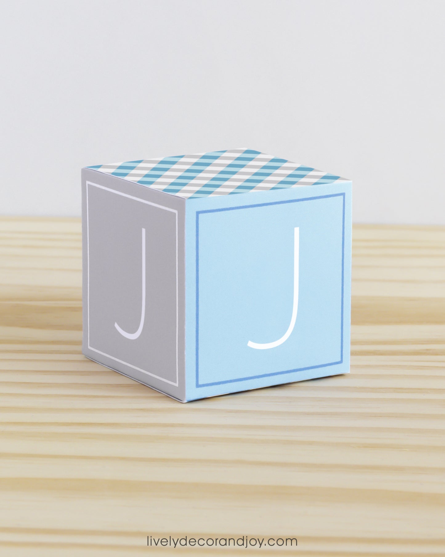 ABC block made of printed paper in tints of blue and light grey. Has the letter J on the sides.