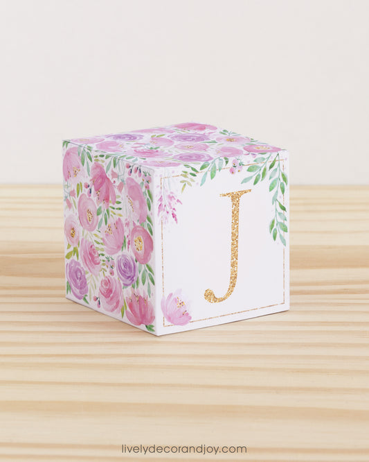 Block made of printed paper with watercolor flowers in blush and lavender. Has a peach letter J on the front.