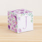 Block made of printed paper with watercolor flowers in purple tones and green leaves. Has a violet letter J on the front.