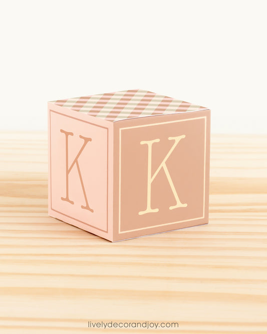 Cube in olive green, pale pink, carrot, peanut brown, and beige. Has the latter K on the sides. It is on a wooden table.