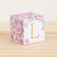 Cube with pink watercolor flowers and green leaves all around but only some on the front, where it has the letter L in gold.