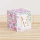 5 minute craft cube with floral designs on a wooden surface. On the front, it has a capital M and a square frame.