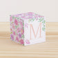 5 minute craft cube with floral designs on a wooden surface. On the front, it has a capital M and a square frame.
