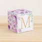 5 minute craft cube with floral designs on a wooden surface. On the front, it has a capital M and a square frame in gold.
