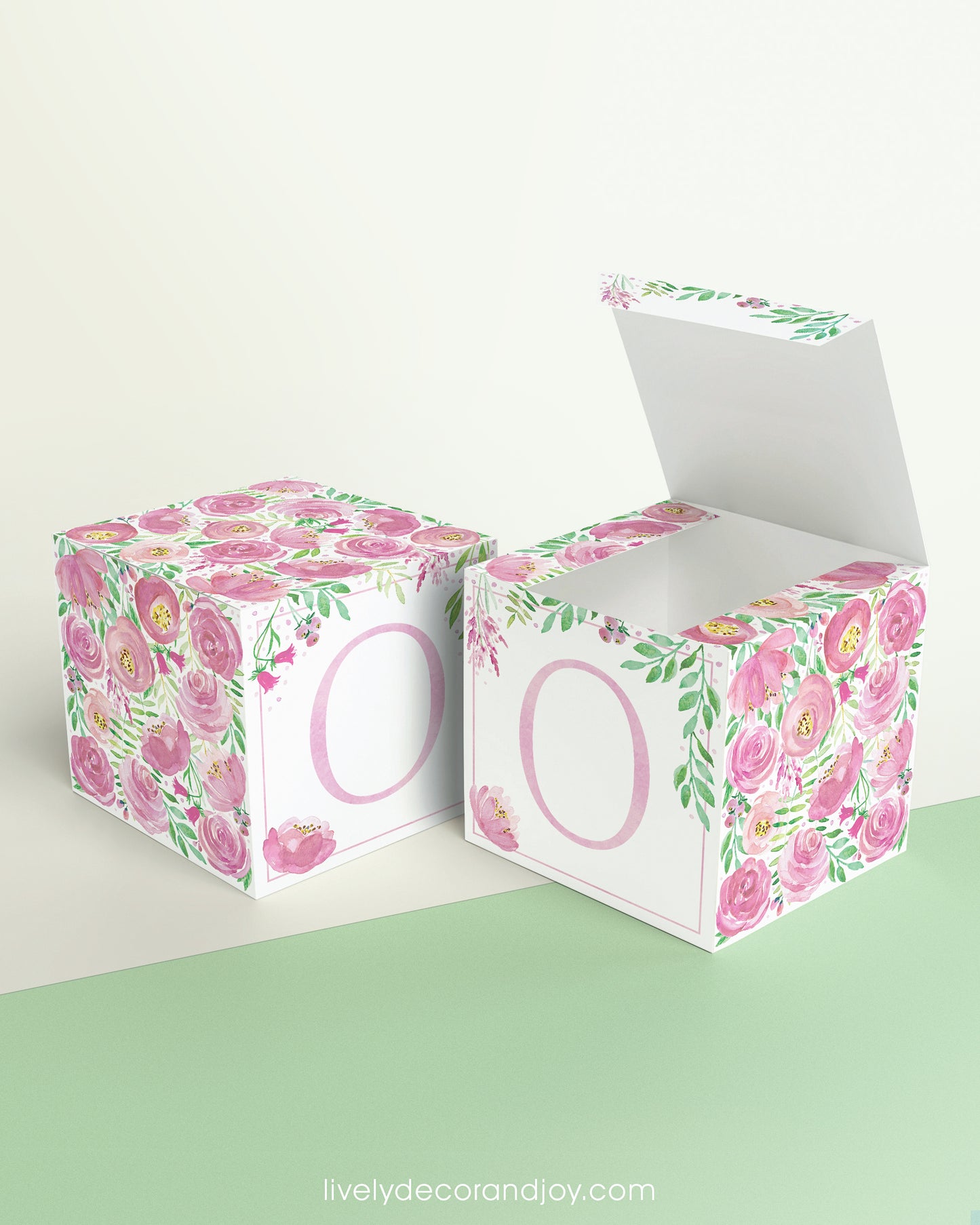 Two printed DIY paper cubes have the same designs, one of which has an open lid, showing that it is a box.