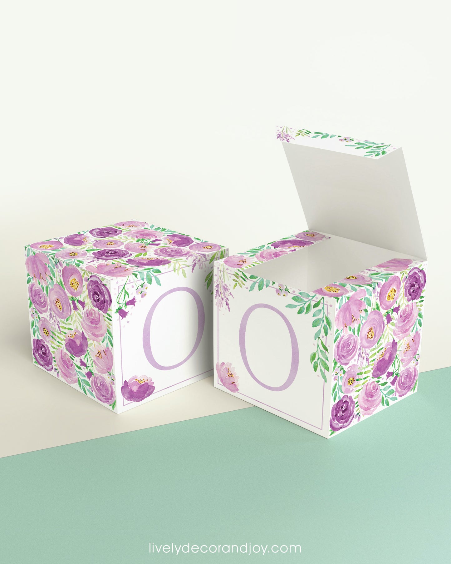 Two printed DIY paper cubes have the same designs, one of which has an open lid, showing that it is a box.