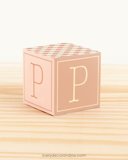 Paper building block in farmhouse colors. It has the letter P on the sides and is on a wood table or shelf.