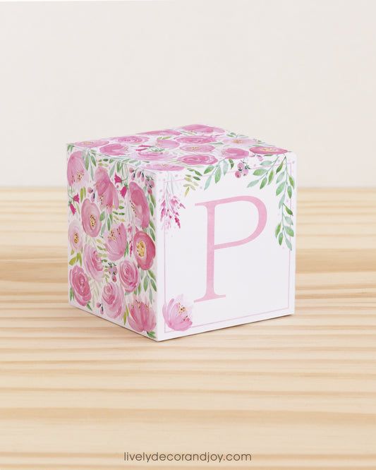 Paper building block features watercolor flowers and leaves in shades of pink and green. A pink letter P is on the front.