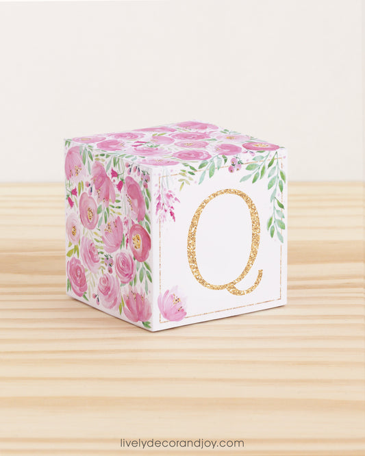 Letter block with printed boho floral designs and a gold letter Q on the front. It is made of paper.