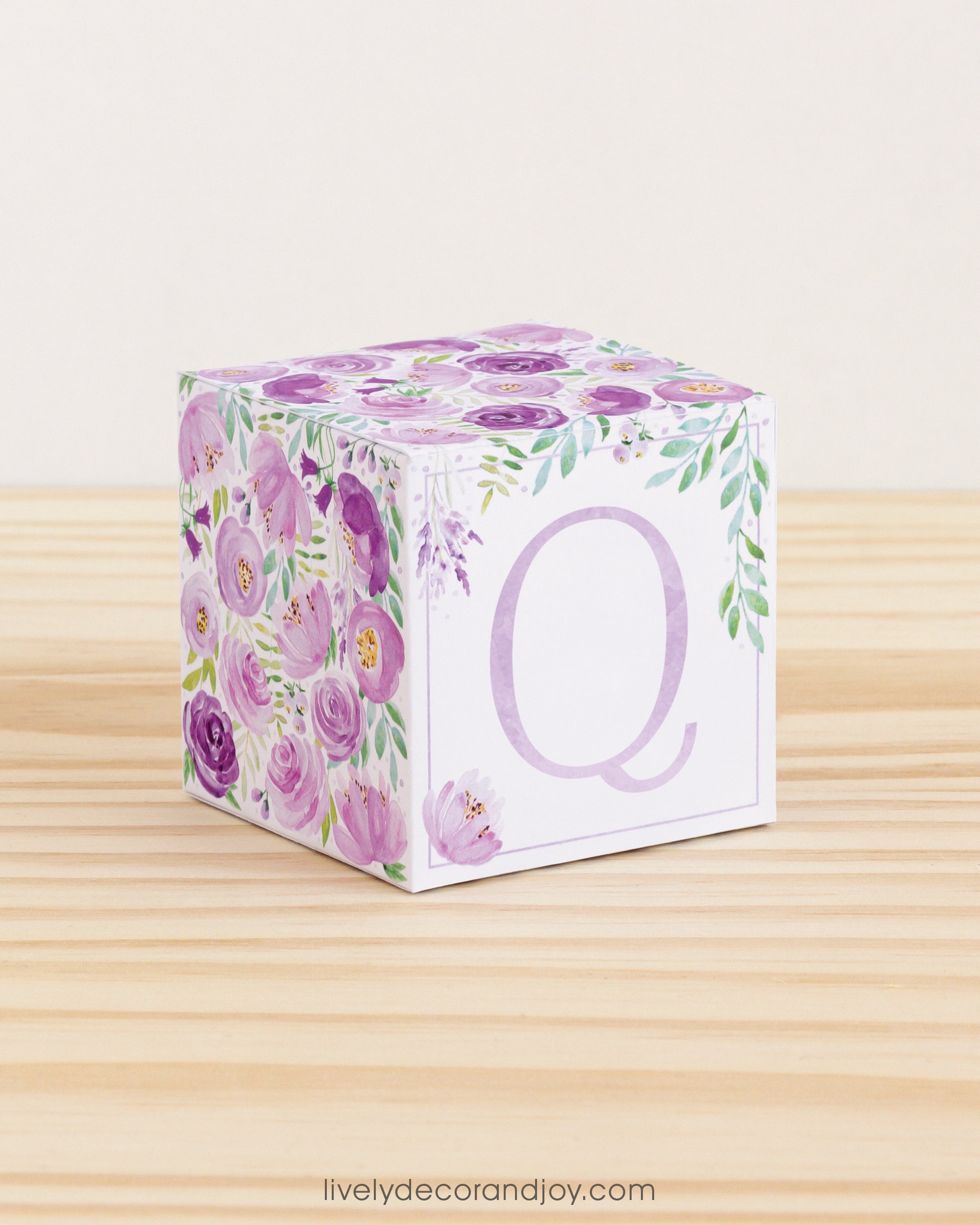 Letter block with printed boho floral designs and a lavender letter Q on the front. It is made of paper.