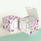 Two blocks made of paper, one has the top lid open. Floral designs cover all sides except the front, which has the letter Q.