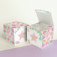Paper building block with floral designs and a star on the front shown both as a cube and as an open box.