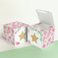 Paper building block with floral designs and a gold star on the front presented twice: as a cube and also as an open box.
