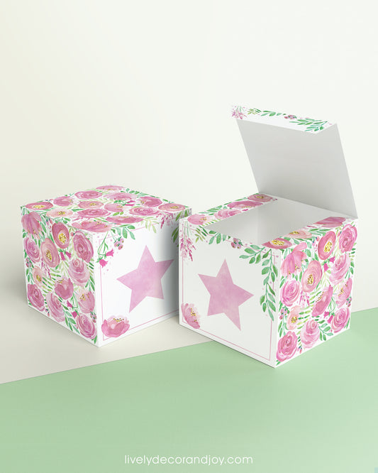 Paper building block with floral designs and a pink star on the front presented twice: as a cube and also as an open box.
