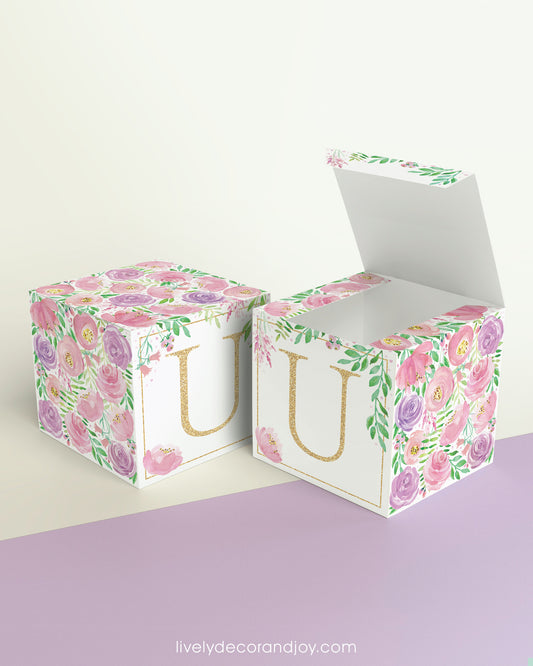 Two printed DIY paper cubes have the same designs, one of which has an open lid, showing that it is a box.