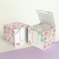 Two printed DIY paper cubes have the same designs, one of which has an open lid, showing that it is a box.