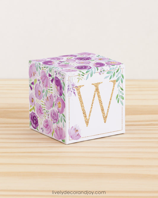 Letter block with printed boho floral designs and a gold letter W on the front. It is made of paper.