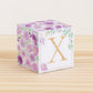 Paper cube with printed boho floral motifs and the letter X on the front. It features purple and green flowers and leaves.