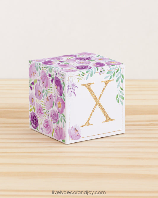 Paper cube with printed boho floral motifs and the letter X on the front. It features purple and green flowers and leaves.