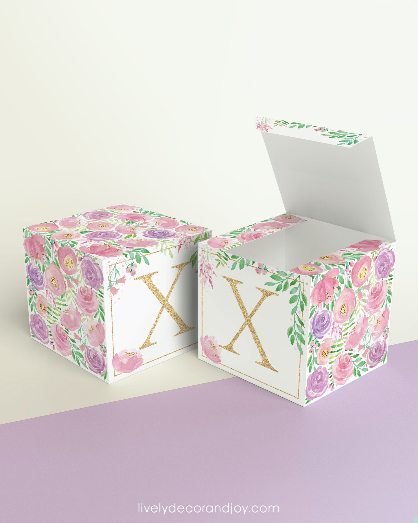 Two identical paper cubes with printed floral designs and the letter X. One has the top open, showing that it is a box.