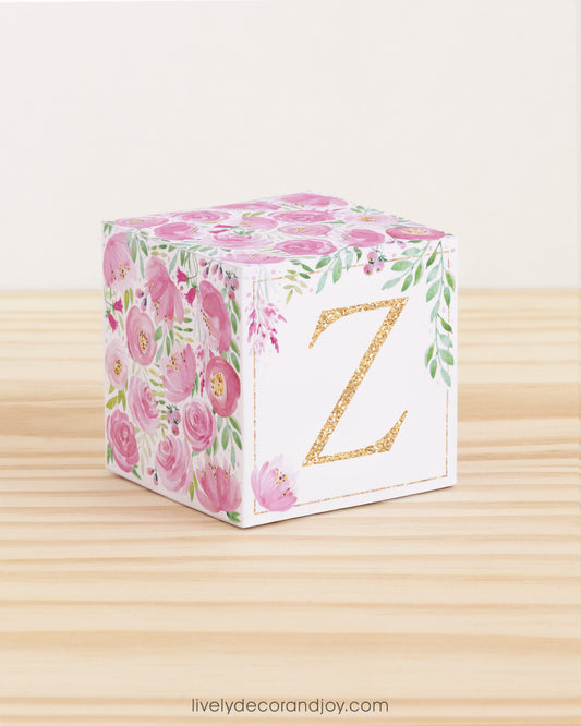 Block made of printed paper with watercolor flowers in pink tones and green leaves. Features a gold letter Z on the front.